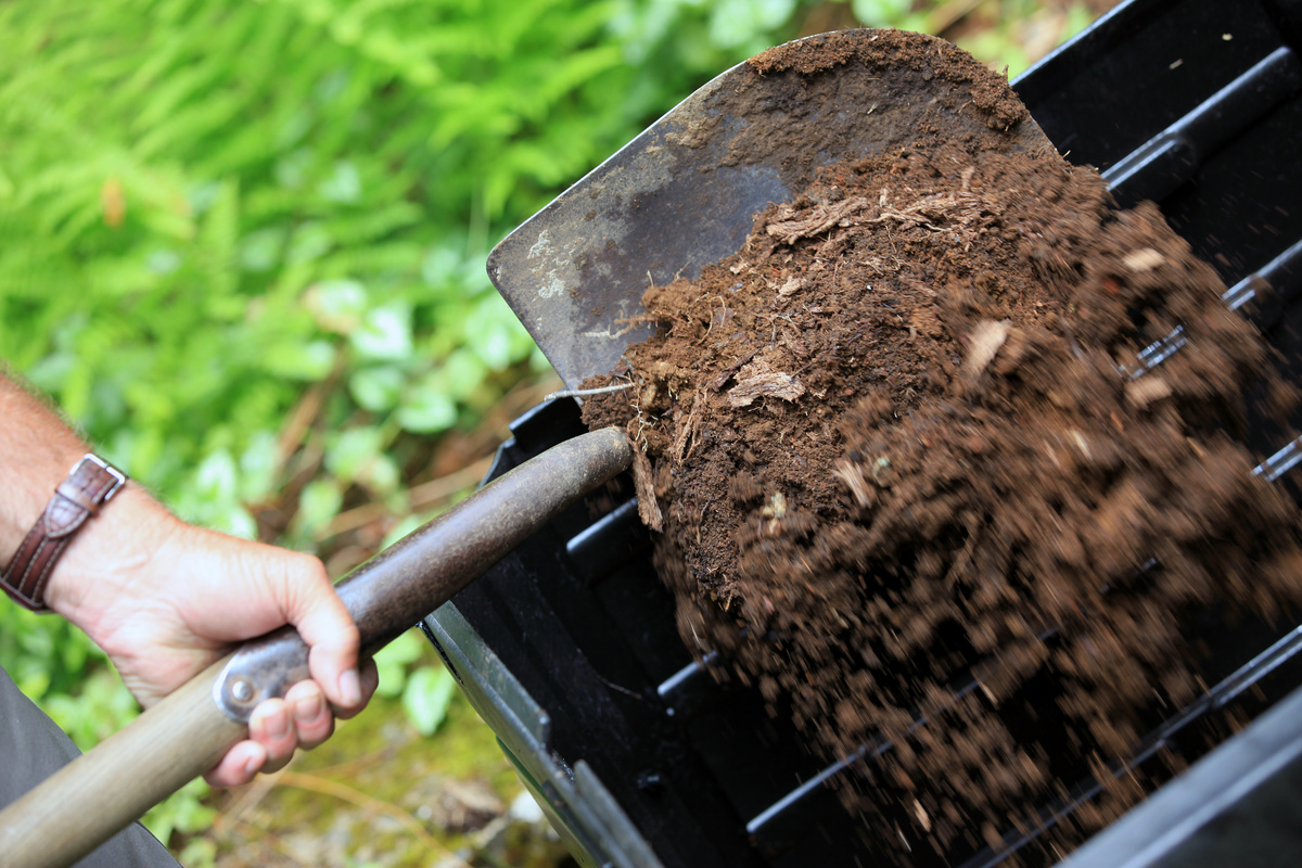 Hand holding shovel full of compost, Home composting