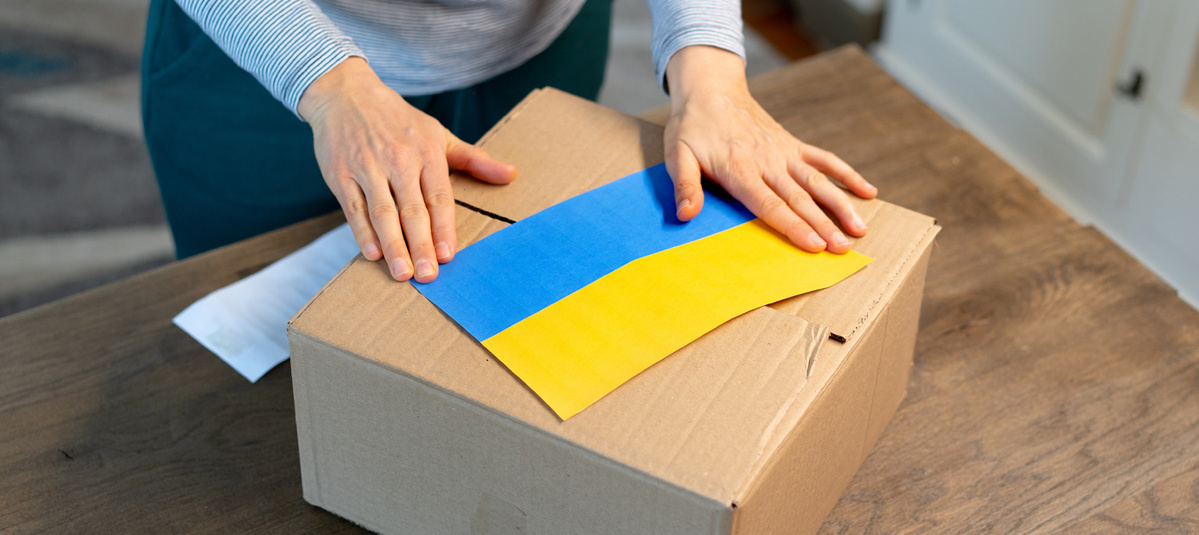 An unrecognisable person is closing a donation box . Help for people in need in Ukraine