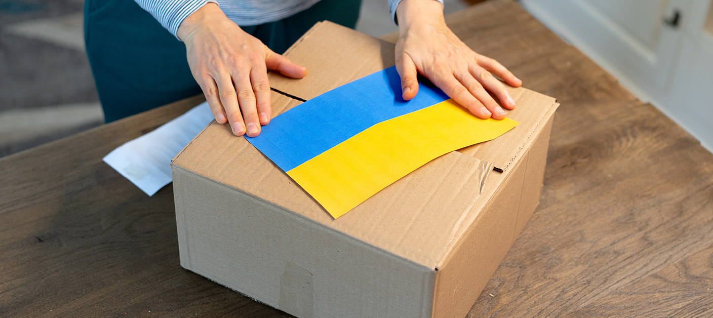 An unrecognisable person is closing a donation box . Help for people in need in Ukraine